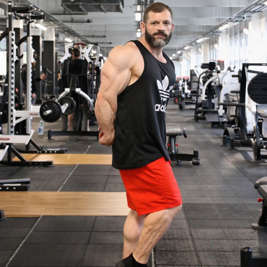 Rich posing side-on in the gym, showing arm and leg conditioning